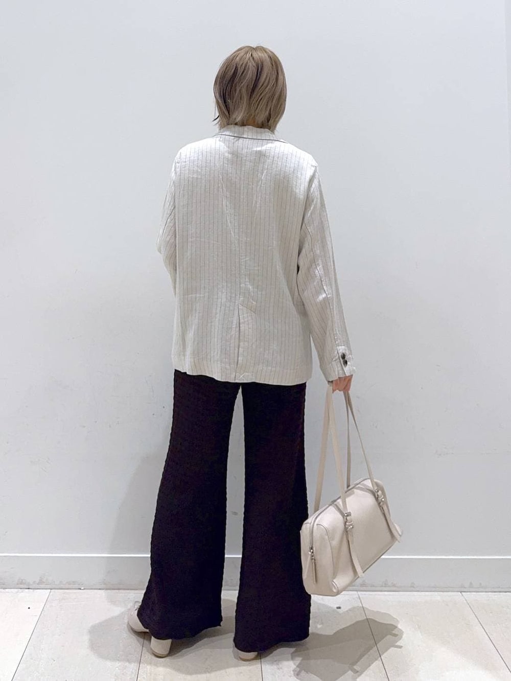 グレー系のテーラードジャケット、ホワイト系のローファー、ベージュ系のショルダーバッグを着用したレディースの春コーディネートの3枚目の写真