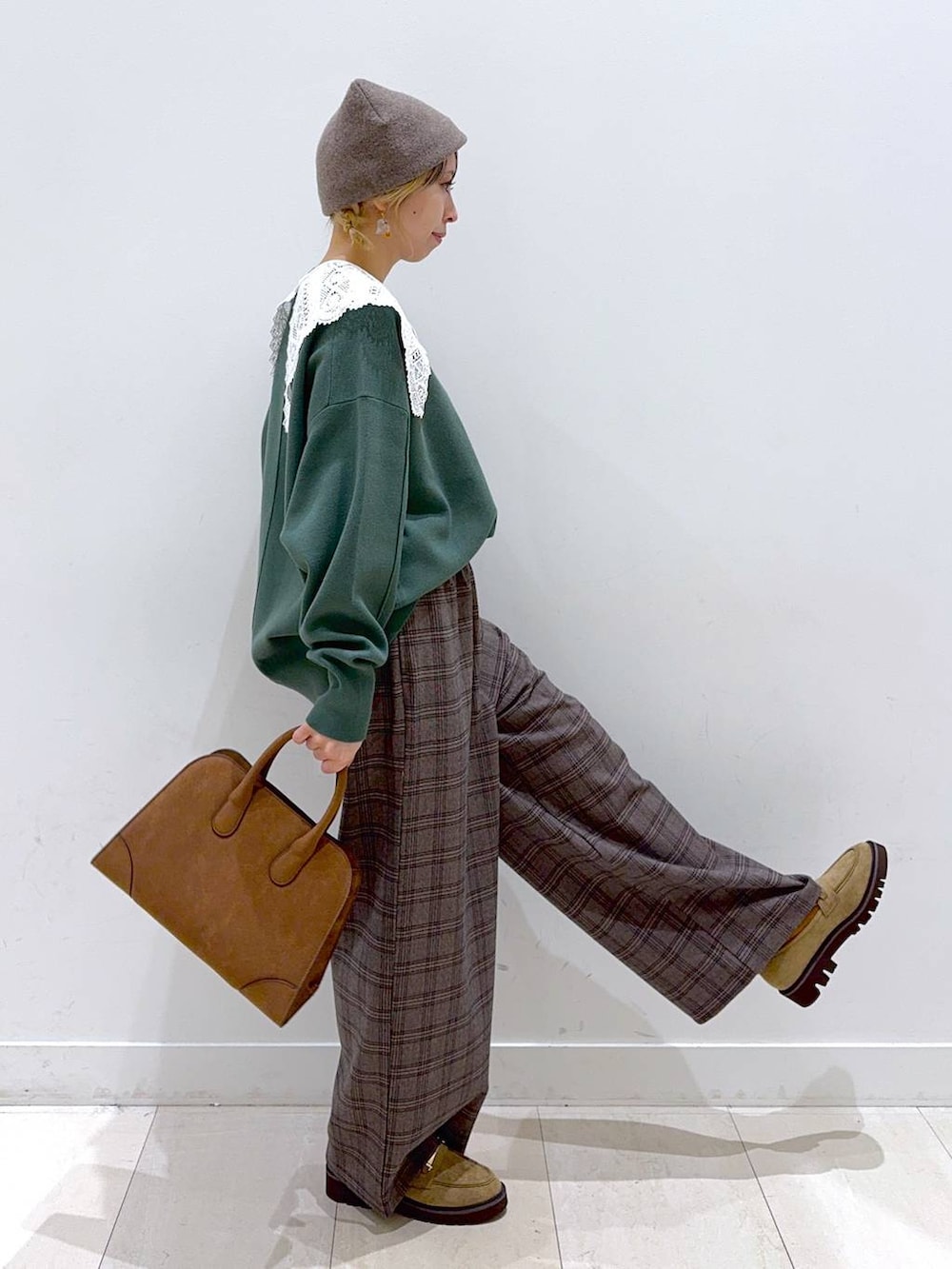 グリーン系のスウェット、ベージュ系のローファー、ベージュ系のショルダーバッグを着用したレディースの秋コーディネートの2枚目の写真