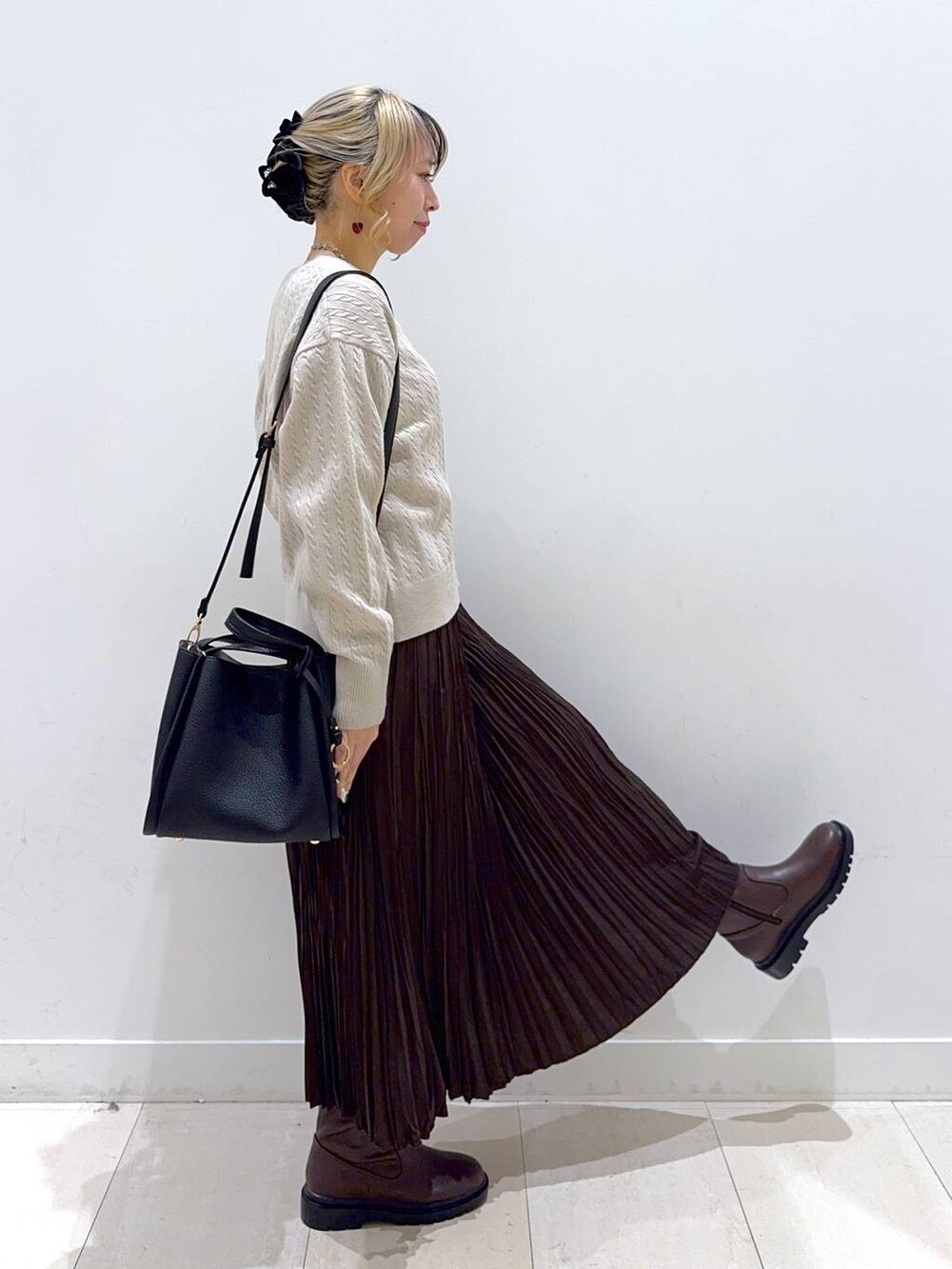 ブラック系のトートバッグ、ブラウン系のブーツ、ブラウン系のスカートを着用したレディースの冬コーディネートの2枚目の写真