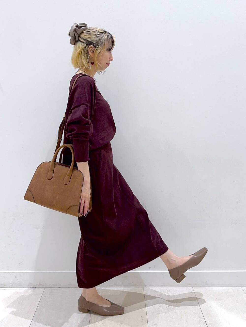 レッド系のニット/セーター、レッド系のスカート、ベージュ系のショルダーバッグを着用したレディースの秋コーディネートの2枚目の写真