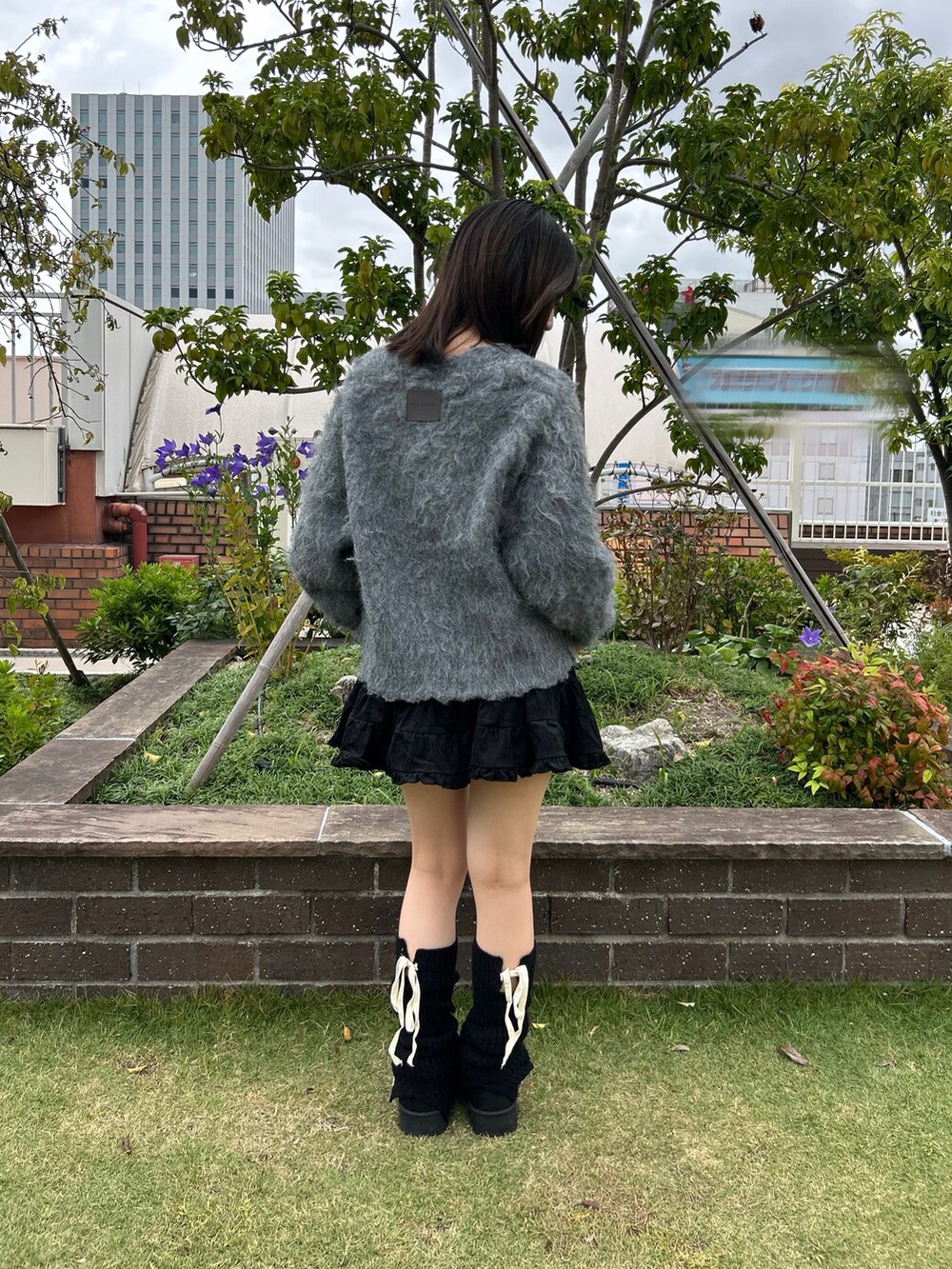 グレー系のカーディガン/ボレロ、ホワイト系のキャミソール、ブラック系のスカートを着用したレディースの秋コーディネートの3枚目の写真