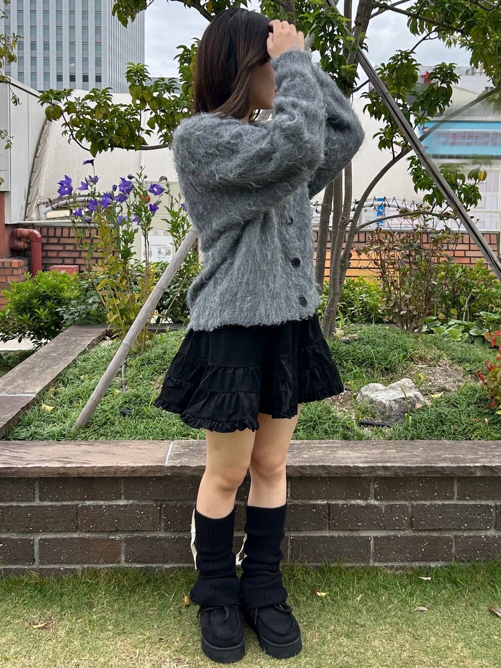 グレー系のカーディガン/ボレロ、ホワイト系のキャミソール、ブラック系のスカートを着用したレディースの秋コーディネートの2枚目の写真