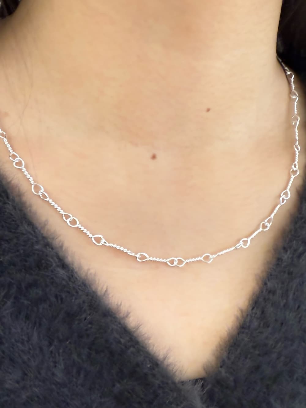 シルバー系のリング、シルバー系のネックレス、シルバー系のブレスレットを着用したレディースの冬コーディネートの2枚目の写真