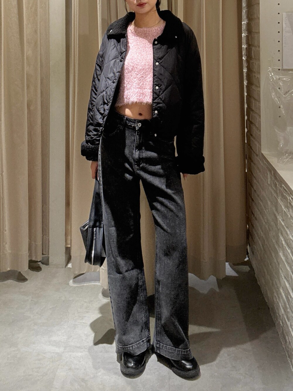 ピンク系のニット/セーター、ブラック系のデニムパンツ、ブラック系のハンドバッグを着用したレディースの秋コーディネートの2枚目の写真