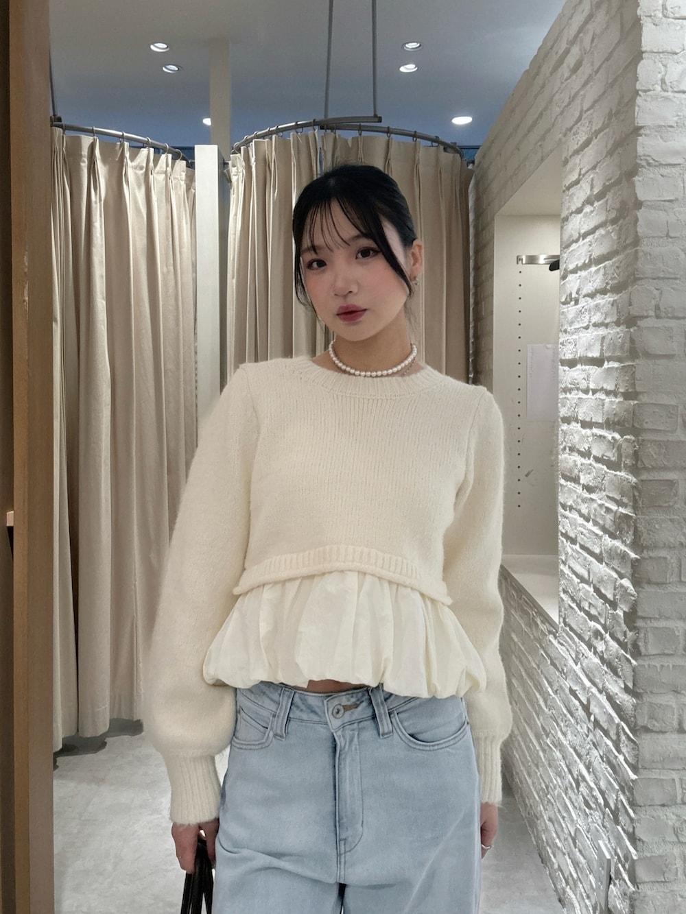 ホワイト系のニット/セーター、ブルー系のデニムパンツ、ブラウン系のトートバッグを着用したレディースの冬コーディネートの3枚目の写真