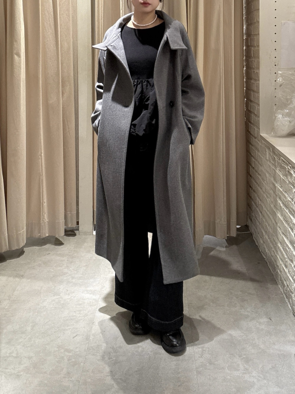 グレー系のステンカラーコート、ブルー系のデニムパンツを着用したレディースの冬コーディネートの2枚目の写真