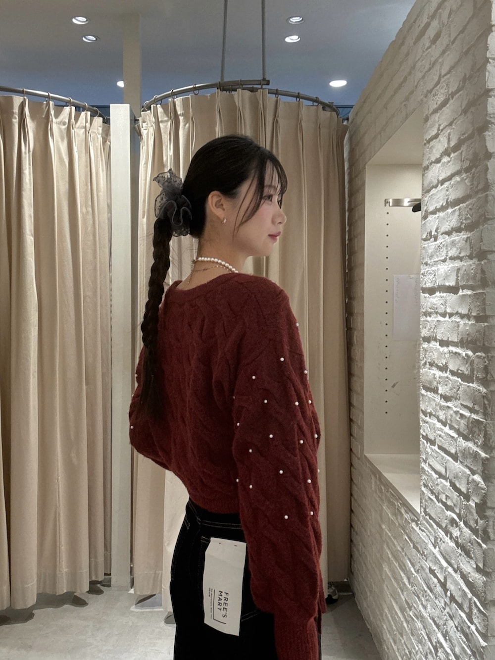 レッド系のニット/セーター、ブルー系のデニムパンツ、ブラウン系のハンドバッグを着用したレディースの冬コーディネートの4枚目の写真