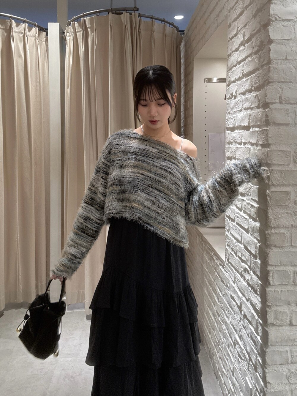 グリーン系のニット/セーター、ブラック系のスカート、ブラック系のショルダーバッグを着用したレディースの秋コーディネートの5枚目の写真