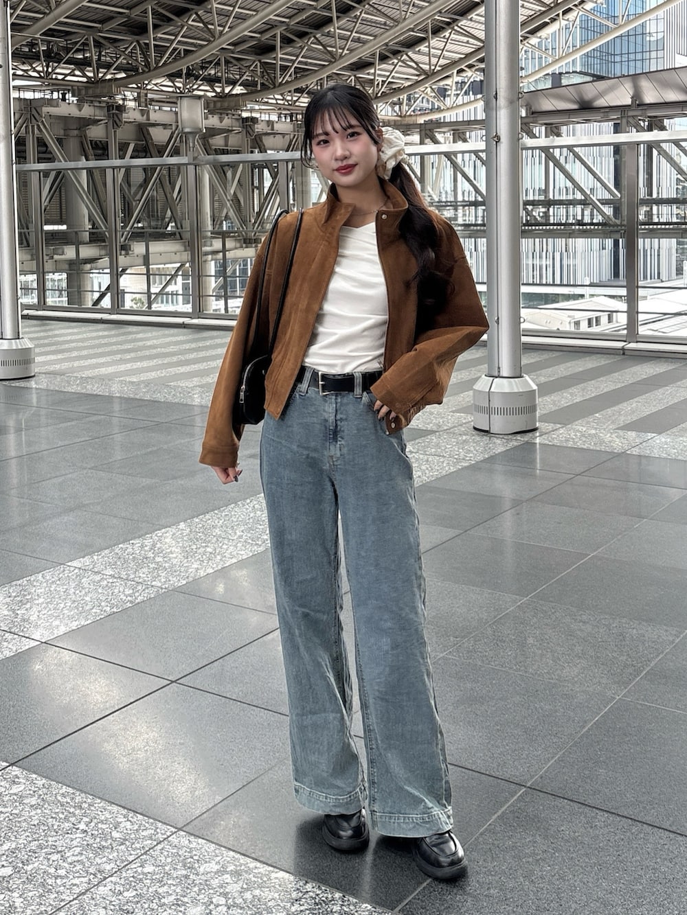 ブラウン系のブルゾン、ブルー系のデニムパンツ、ホワイト系のTシャツ/カットソーを着用したレディースの冬コーディネートの2枚目の写真