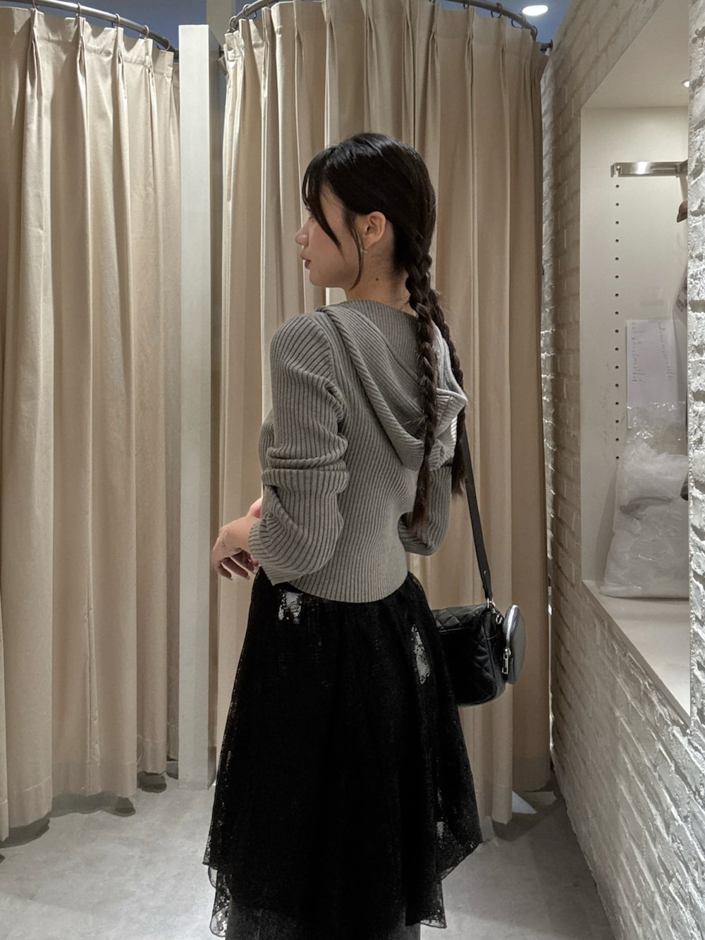 ブラウン系のニット/セーター、ブラック系のスカート、ブラック系のデニムパンツを着用したレディースの秋コーディネートの5枚目の写真