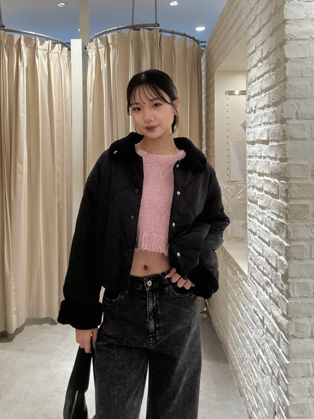 ピンク系のニット/セーター、ブラック系のデニムパンツ、ブラック系のハンドバッグを着用したレディースの秋コーディネートの3枚目の写真