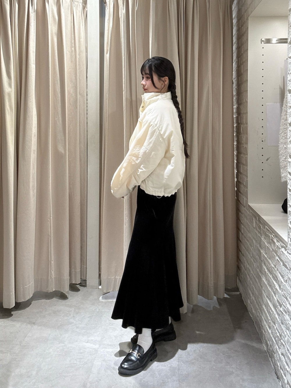 ホワイト系のブルゾン、ブラック系のスカートを着用したレディースの冬コーディネートの3枚目の写真