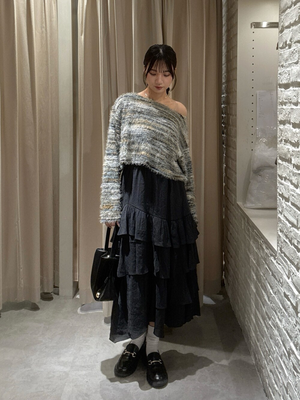 グリーン系のニット/セーター、ブラック系のスカート、ブラック系のショルダーバッグを着用したレディースの秋コーディネートの2枚目の写真