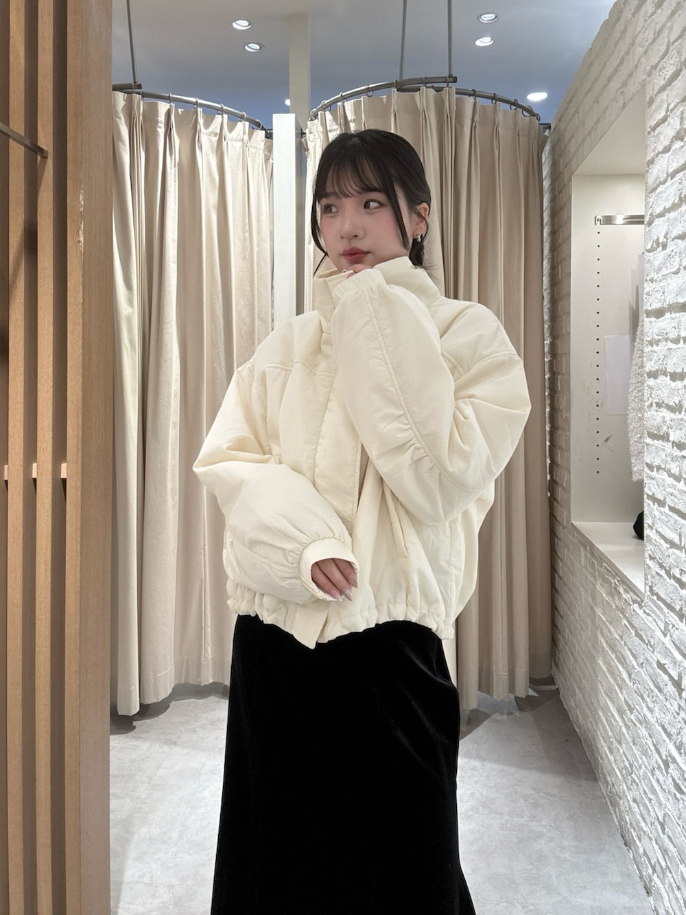 ホワイト系のブルゾン、ブラック系のスカートを着用したレディースの冬コーディネートの4枚目の写真