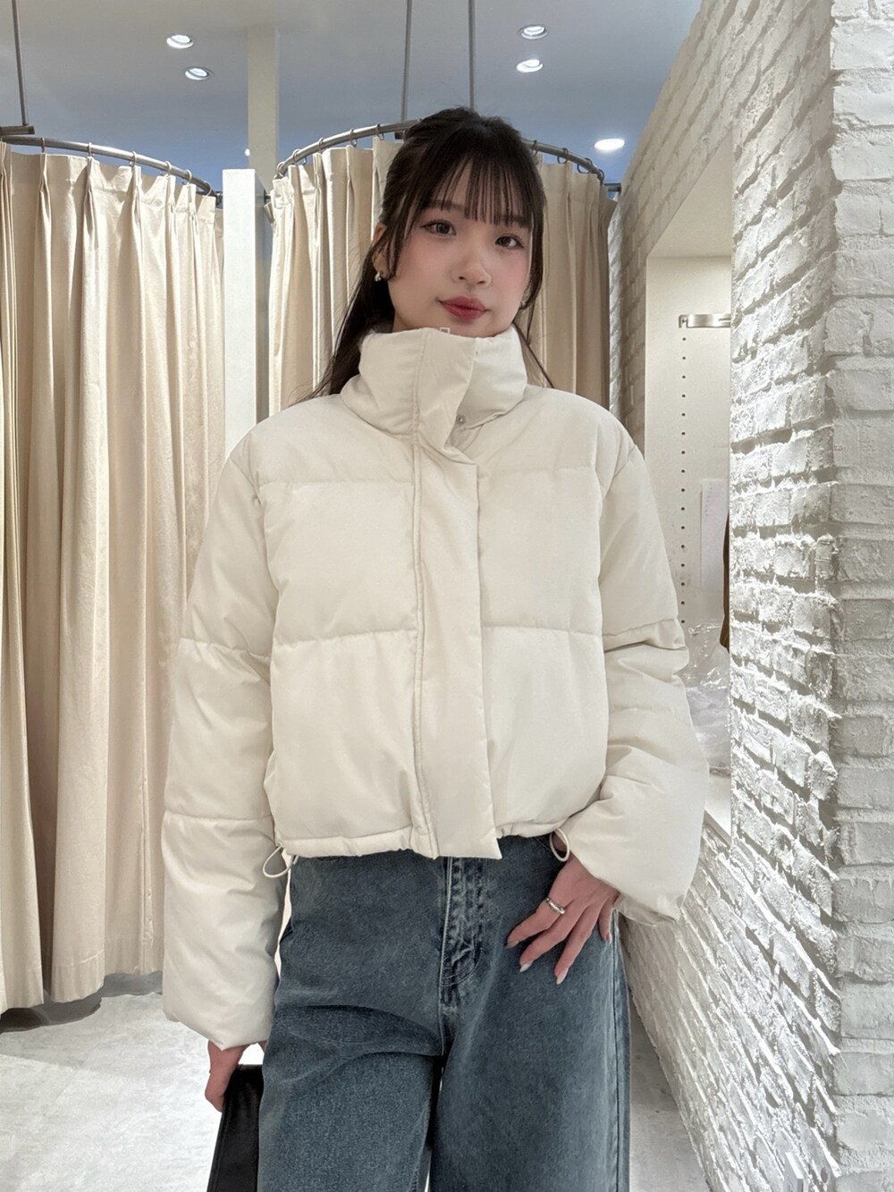 ホワイト系のブルゾン、ブルー系のデニムパンツを着用したレディースの冬コーディネートの4枚目の写真