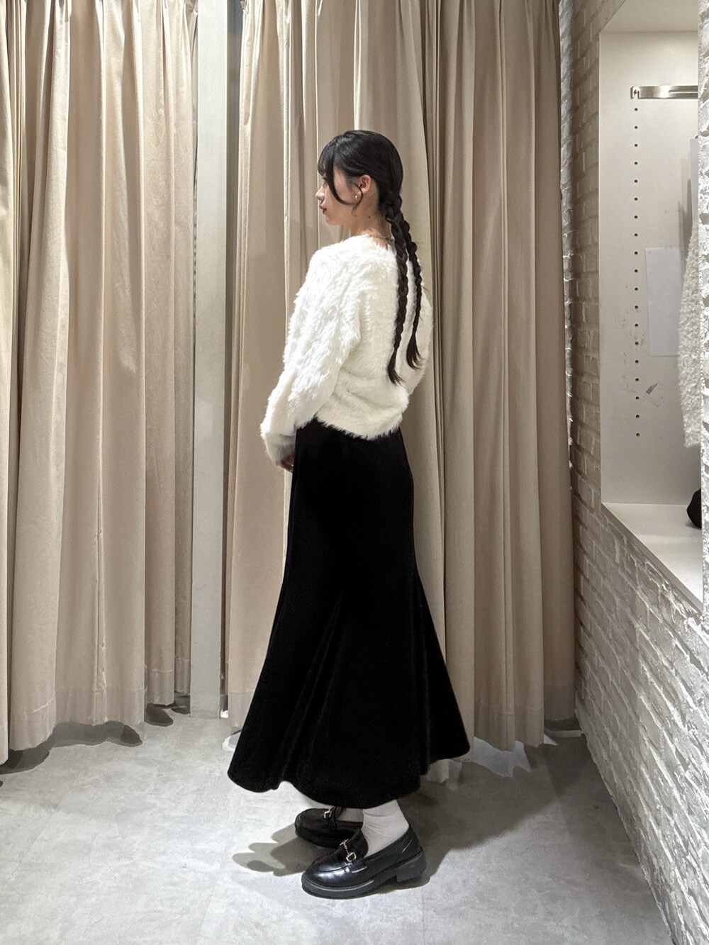 ホワイト系のニット/セーター、ブラック系のスカートを着用したレディースの冬コーディネートの2枚目の写真