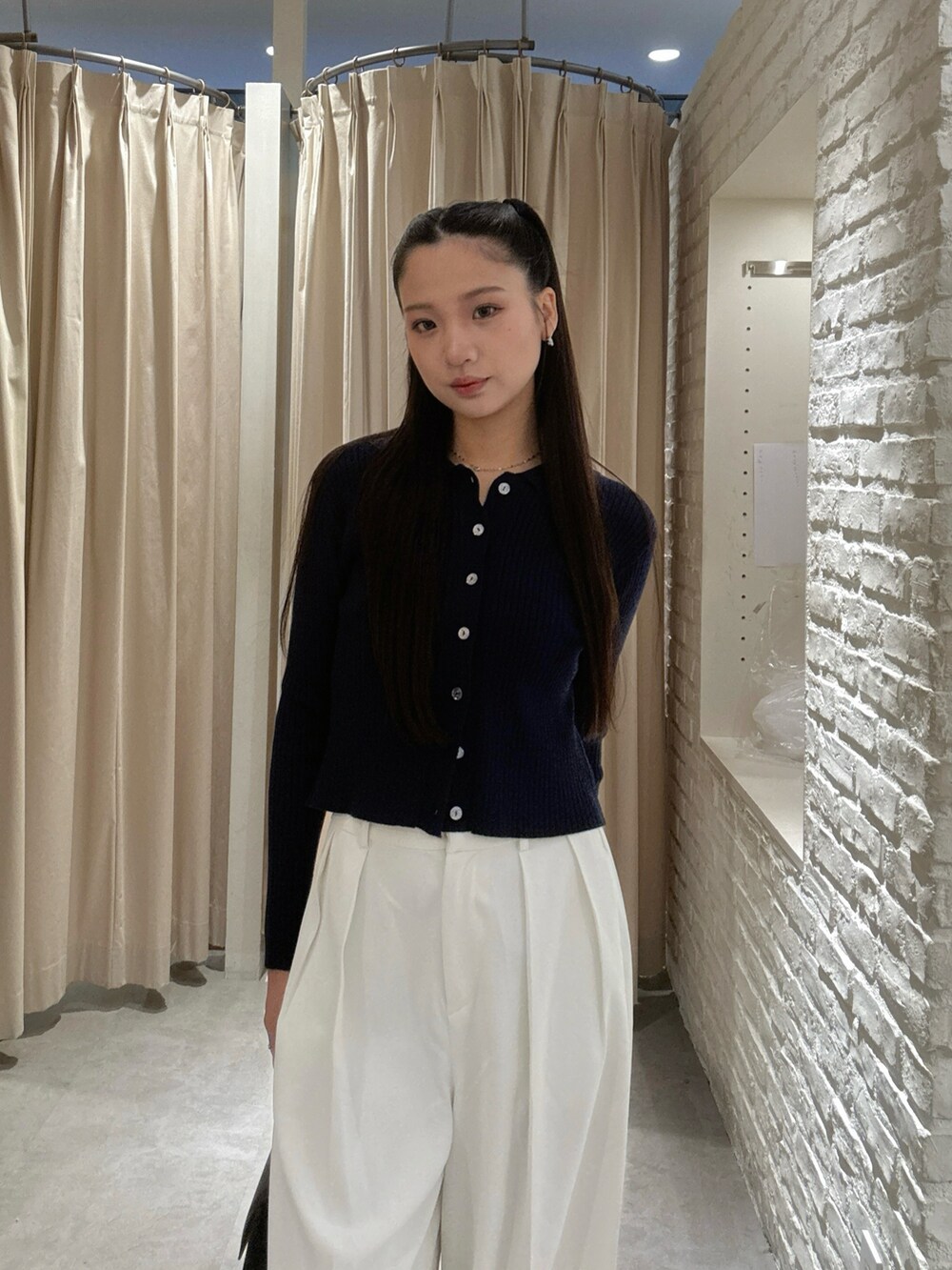 ホワイト系のスラックス、ブラック系のトートバッグを着用したレディースの秋コーディネートの3枚目の写真