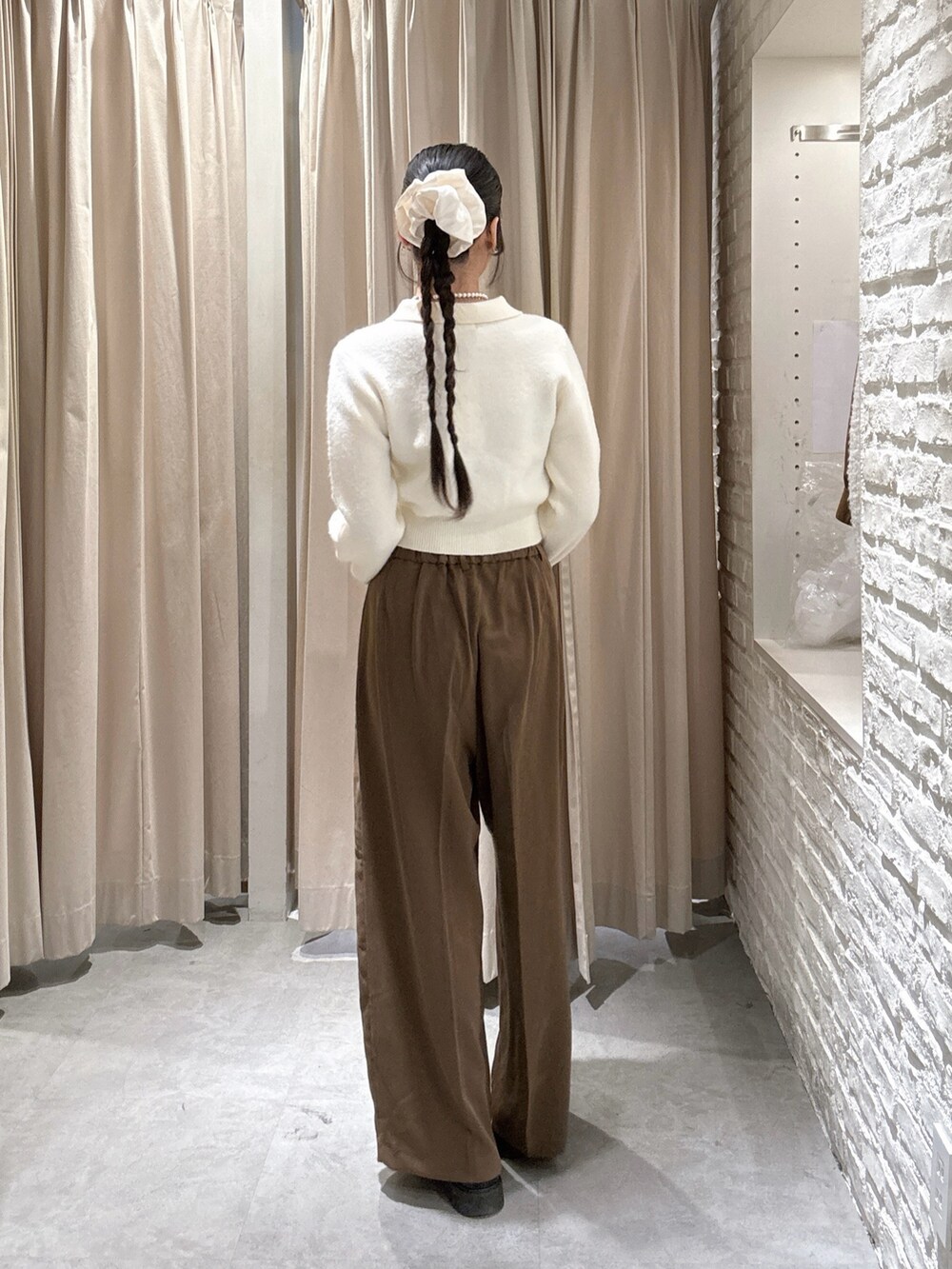 ホワイト系のニット/セーター、ブラウン系のスラックスを着用したレディースの冬コーディネートの2枚目の写真