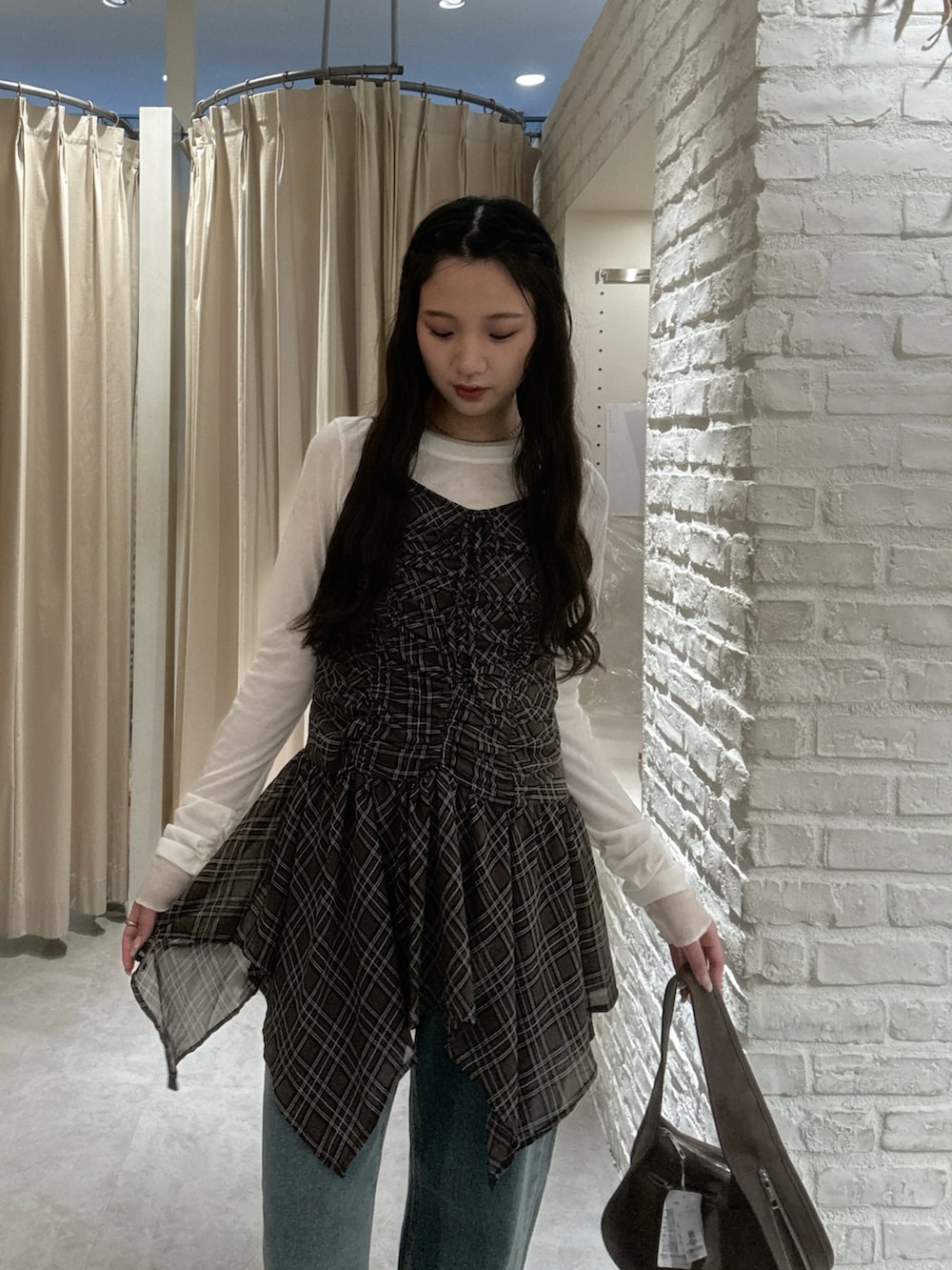 ブラウン系のワンピース、ホワイト系のTシャツ/カットソー、ブルー系のデニムパンツを着用したレディースの秋コーディネートの5枚目の写真