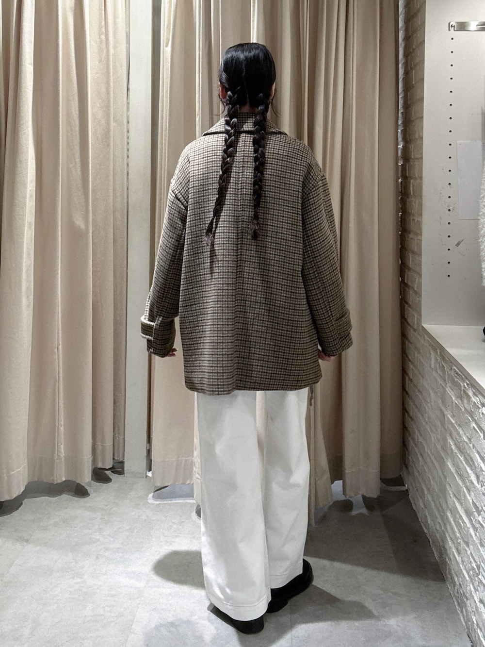 ベージュ系のピーコート、ホワイト系のデニムパンツ、ブラウン系のニット/セーターを着用したレディースの冬コーディネートの2枚目の写真