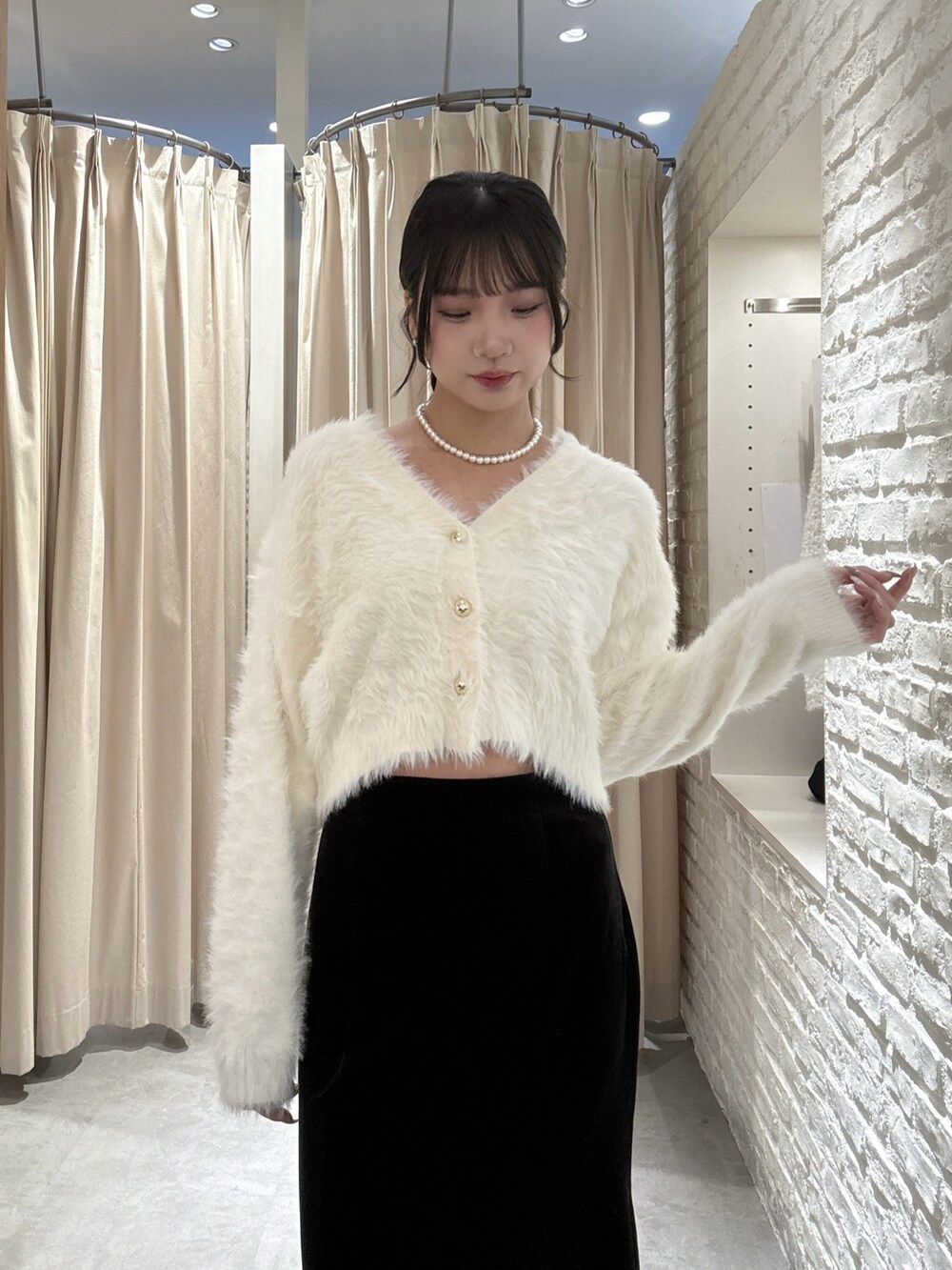 ホワイト系のニット/セーター、ブラック系のスカートを着用したレディースの冬コーディネートの3枚目の写真