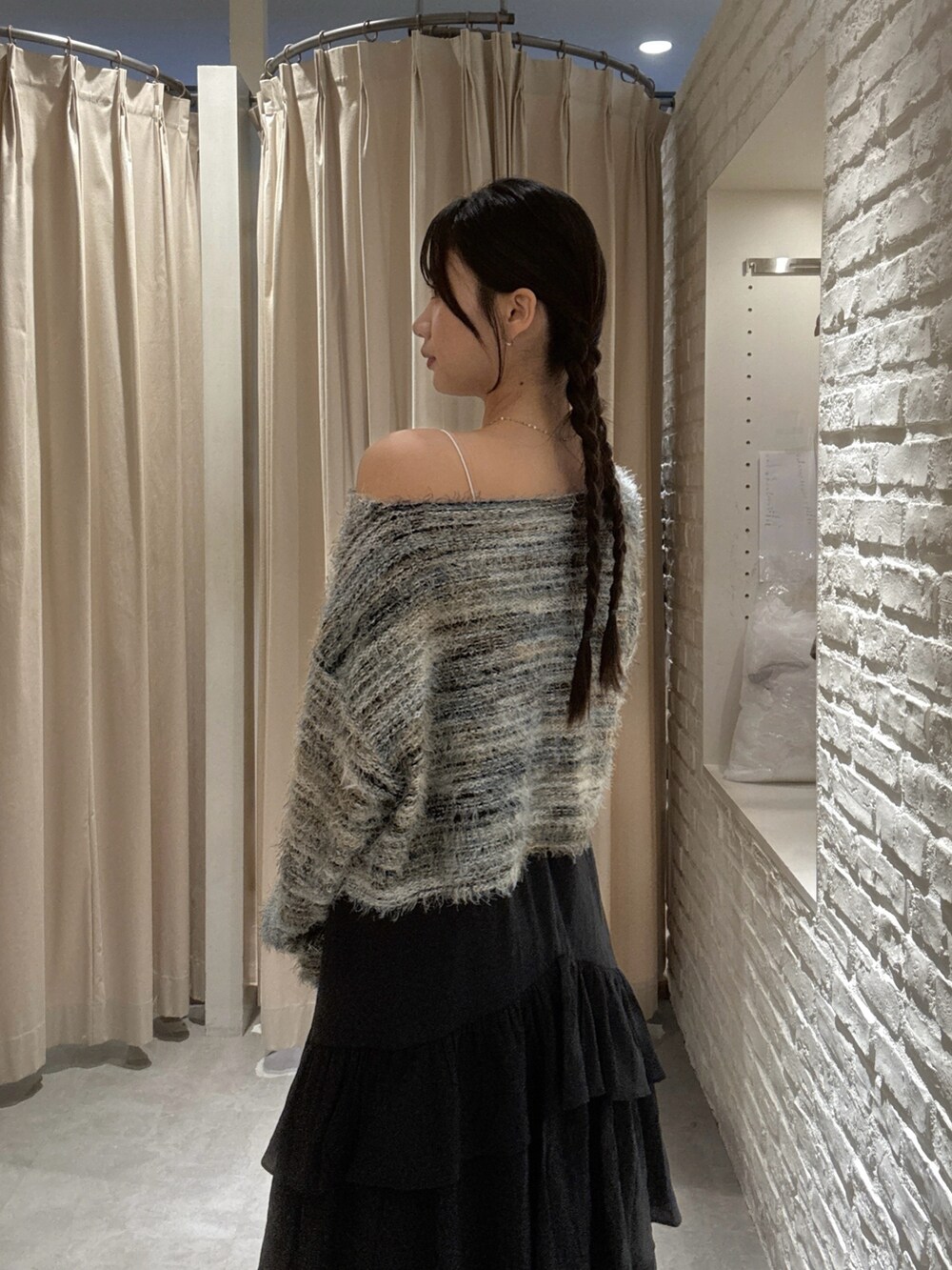 グリーン系のニット/セーター、ブラック系のスカート、ブラック系のショルダーバッグを着用したレディースの秋コーディネートの4枚目の写真