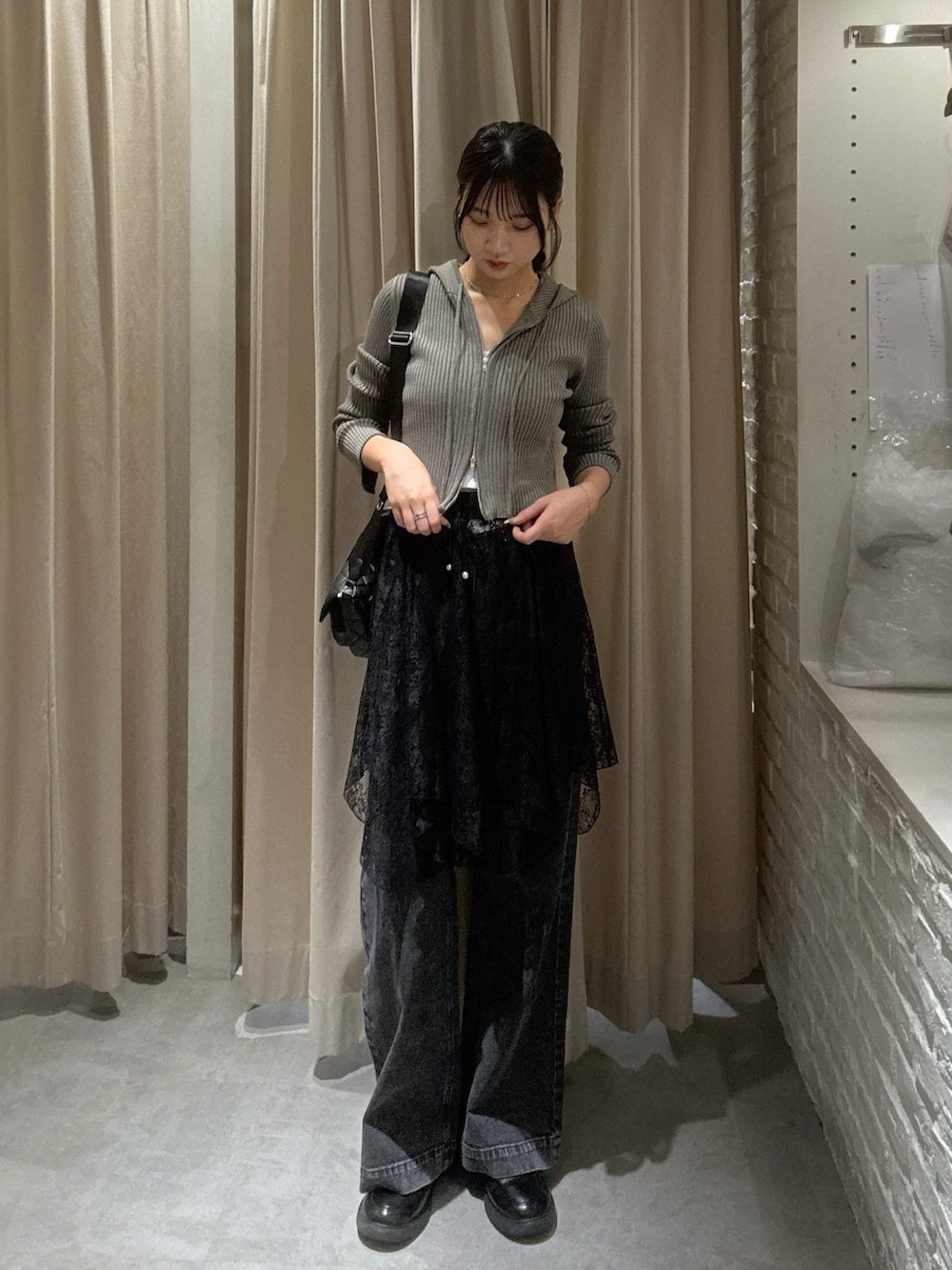 ブラウン系のニット/セーター、ブラック系のスカート、ブラック系のデニムパンツを着用したレディースの秋コーディネートの2枚目の写真