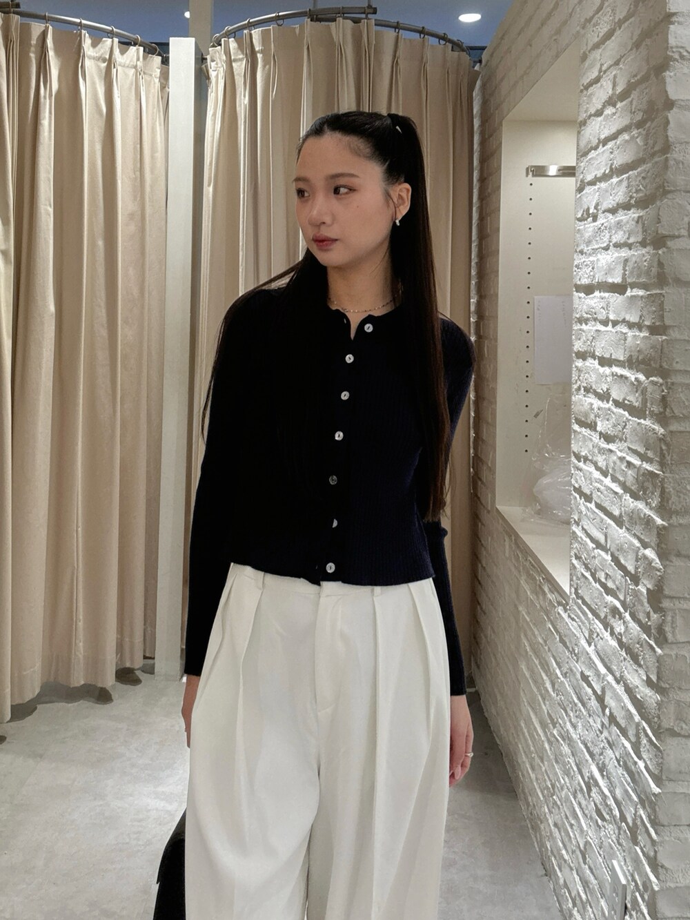 ホワイト系のスラックス、ブラック系のトートバッグを着用したレディースの秋コーディネートの4枚目の写真