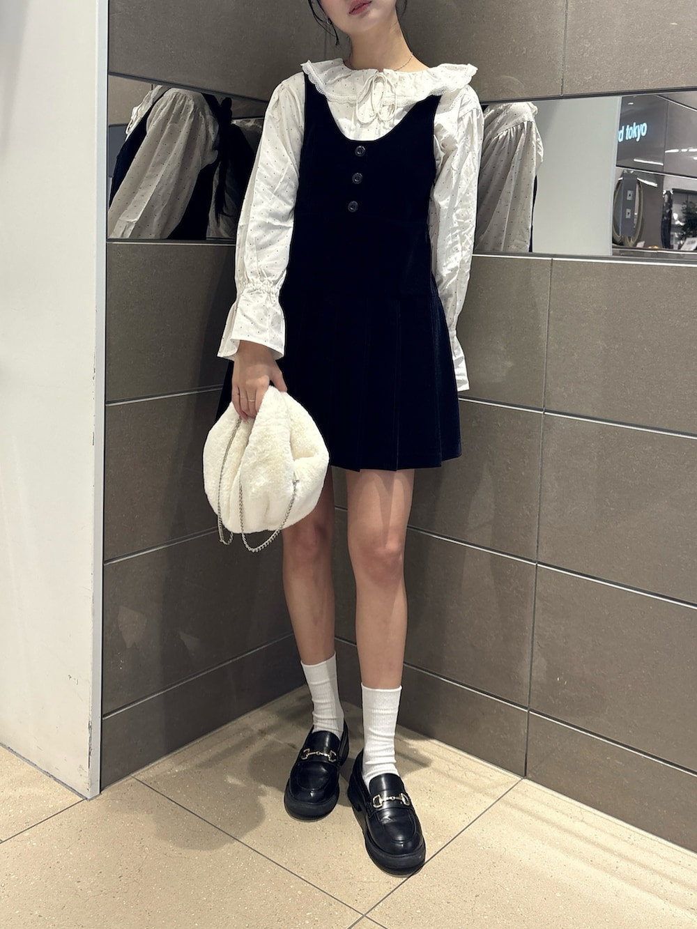 ブルー系のジャンパースカート、ホワイト系のハンドバッグ、ホワイト系のシャツ/ブラウスを着用したレディースの冬コーディネートの2枚目の写真