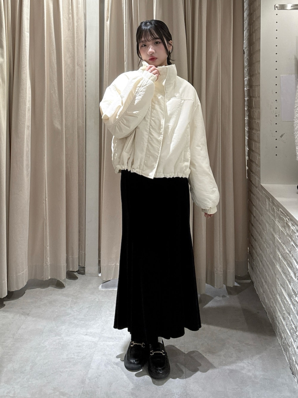 ホワイト系のブルゾン、ブラック系のスカートを着用したレディースの冬コーディネートの2枚目の写真