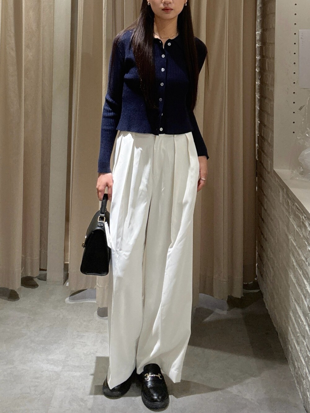 ホワイト系のスラックス、ブラック系のトートバッグを着用したレディースの秋コーディネートの2枚目の写真