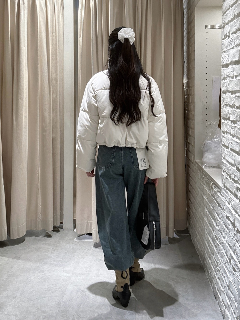 ホワイト系のブルゾン、ブルー系のデニムパンツを着用したレディースの冬コーディネートの3枚目の写真