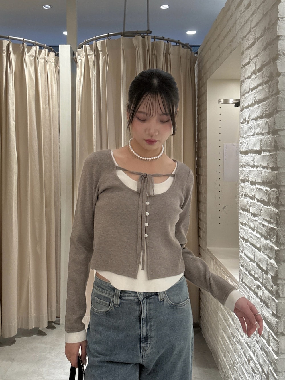 ブラウン系のニット/セーター、ブルー系のデニムパンツ、ブラック系のショルダーバッグを着用したレディースの冬コーディネートの4枚目の写真