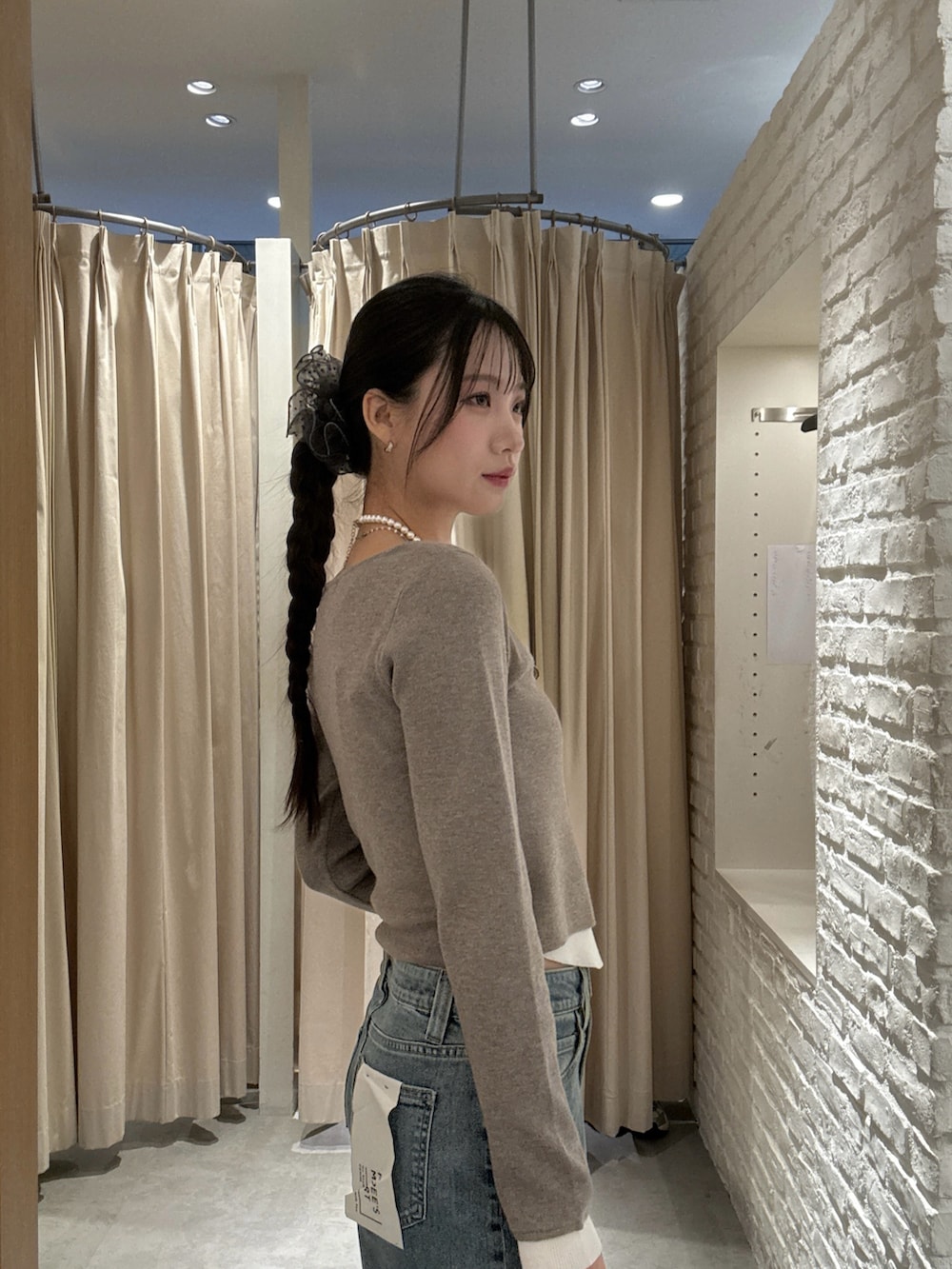 ブラウン系のニット/セーター、ブルー系のデニムパンツ、ブラック系のショルダーバッグを着用したレディースの冬コーディネートの3枚目の写真