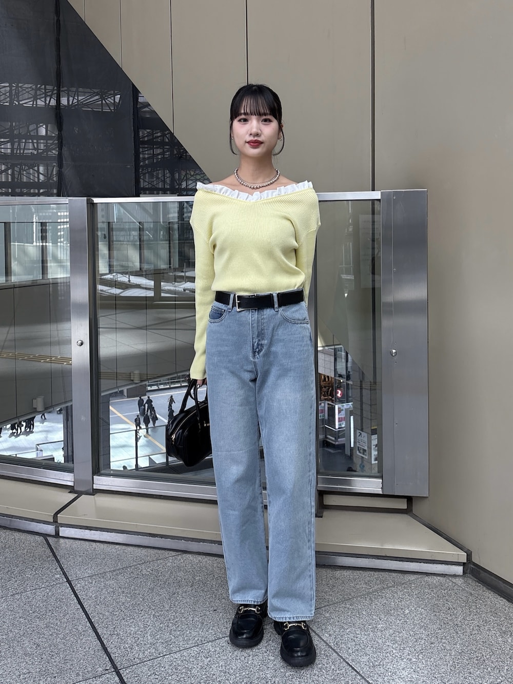 イエロー系のニット/セーター、ブルー系のデニムパンツを着用したレディースの冬コーディネートの2枚目の写真