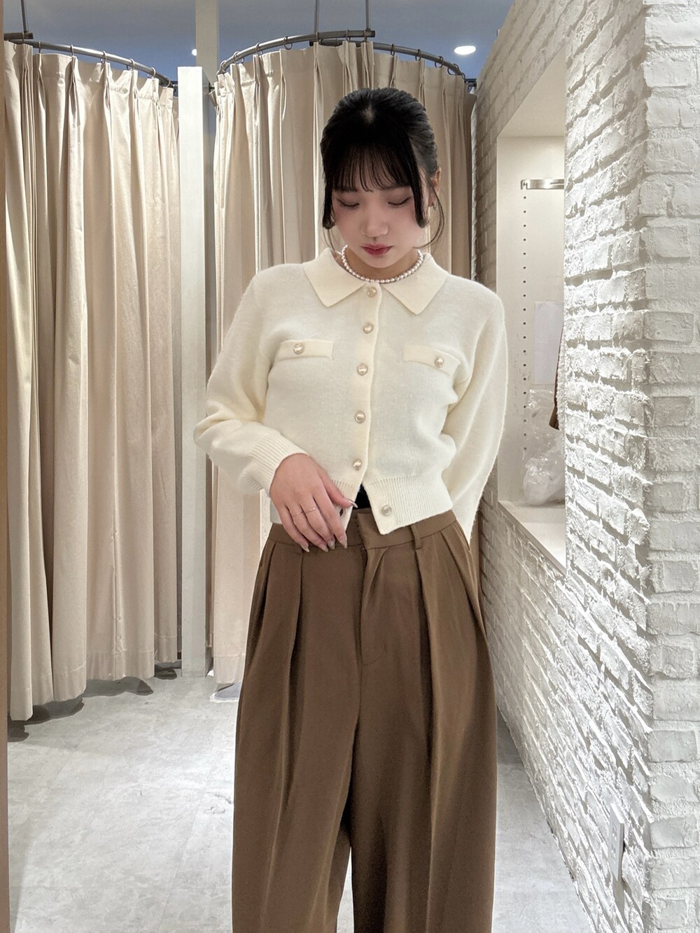 ホワイト系のニット/セーター、ブラウン系のスラックスを着用したレディースの冬コーディネートの3枚目の写真