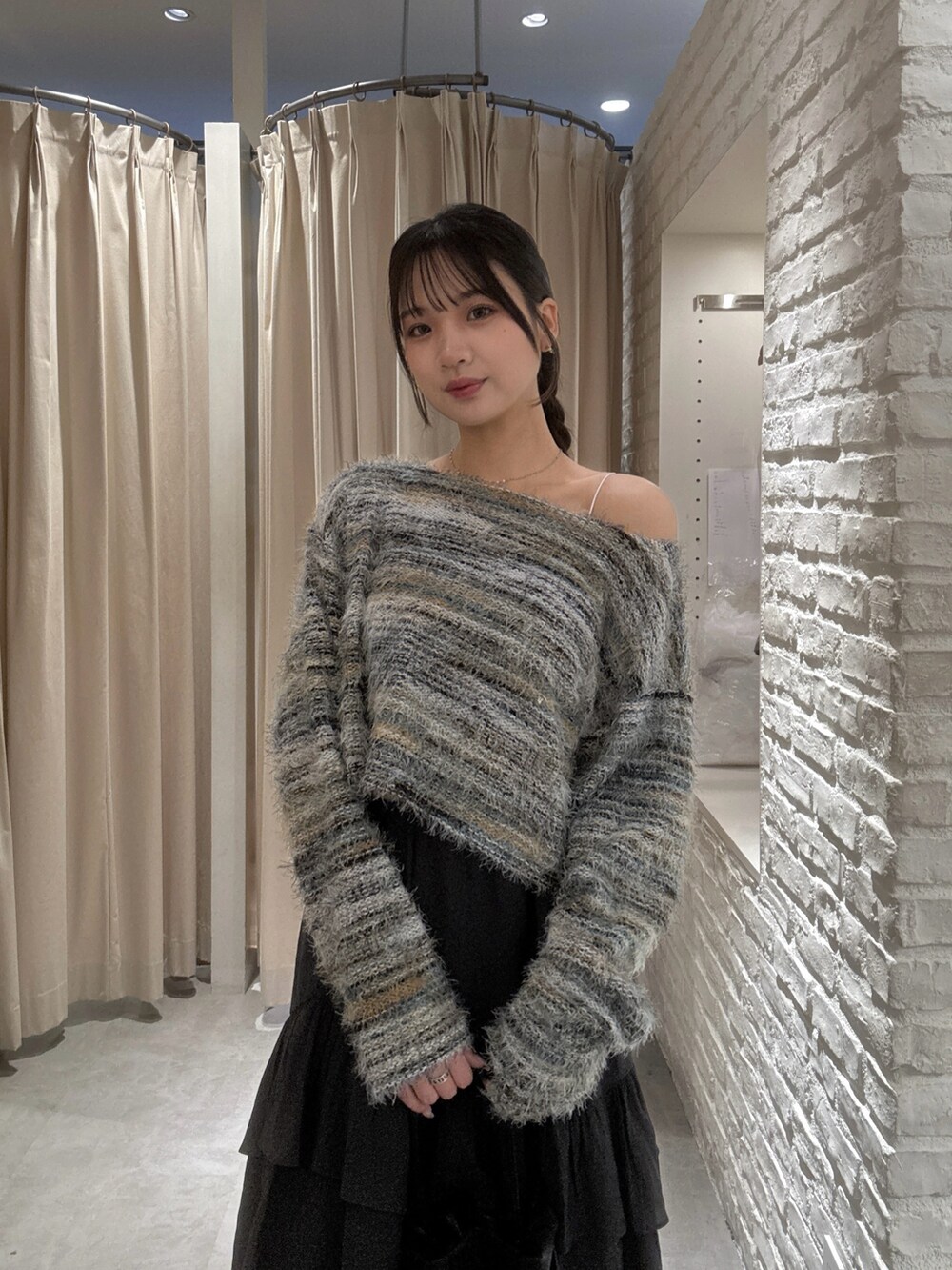 グリーン系のニット/セーター、ブラック系のスカート、ブラック系のショルダーバッグを着用したレディースの秋コーディネートの3枚目の写真