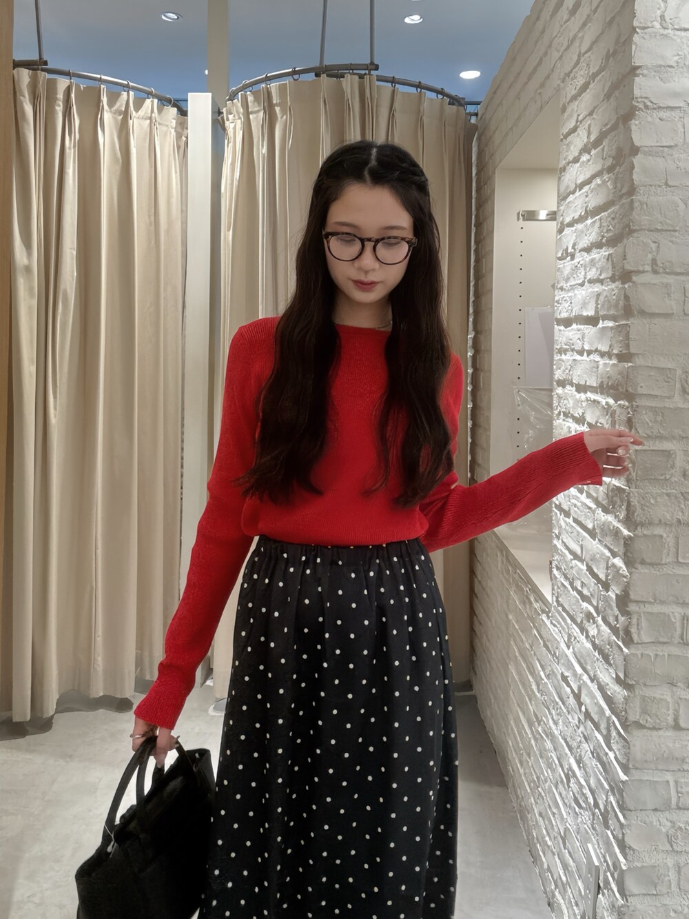 レッド系のニット/セーター、ブラック系のスカート、ブラウン系のサングラスを着用したレディースの秋コーディネートの3枚目の写真