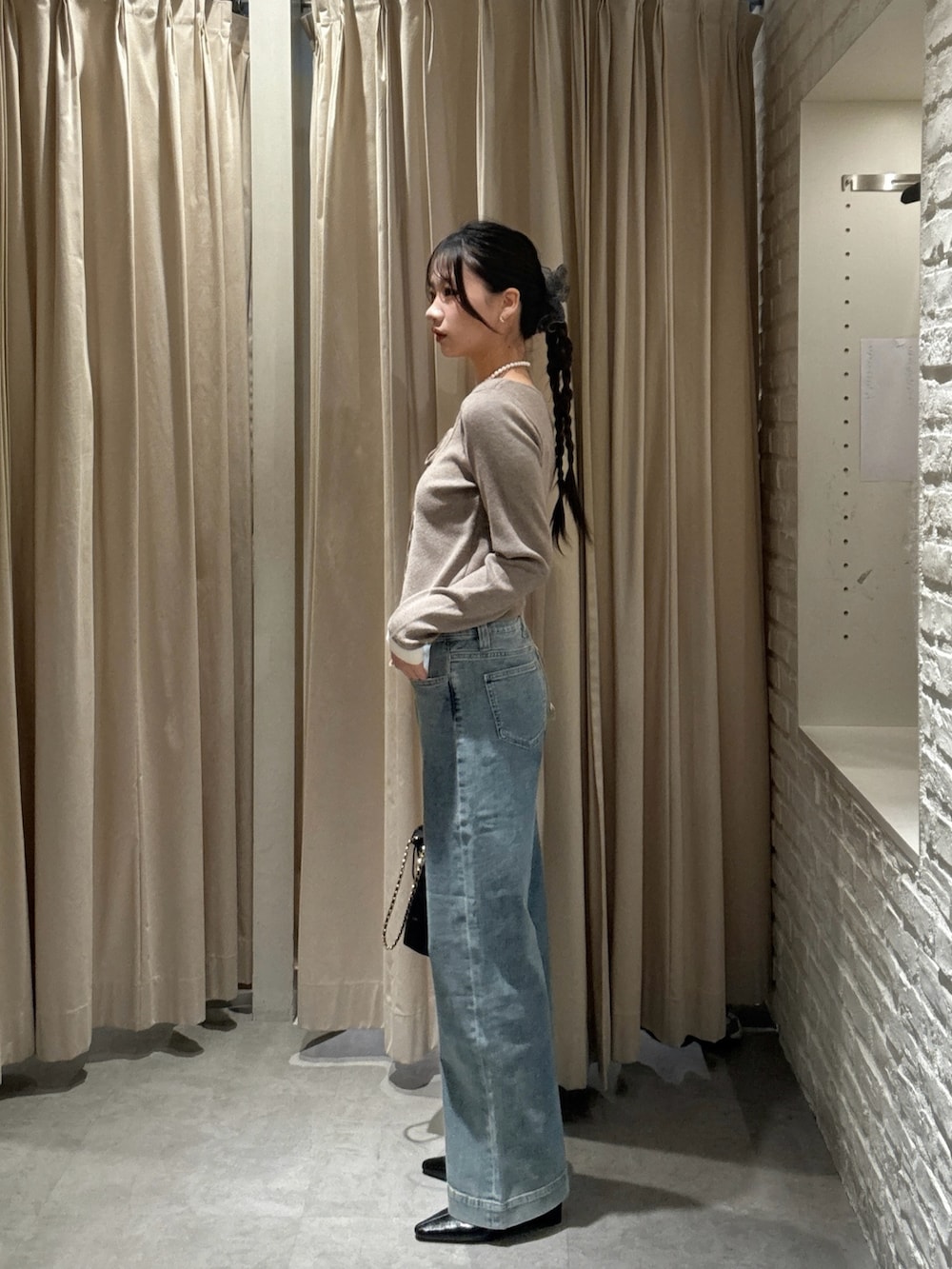 ブラウン系のニット/セーター、ブルー系のデニムパンツ、ブラック系のショルダーバッグを着用したレディースの冬コーディネートの2枚目の写真