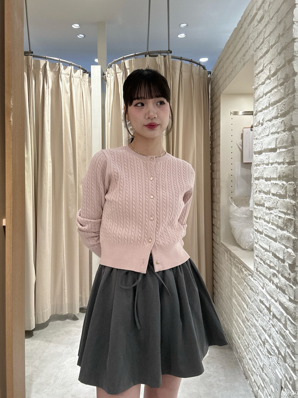 ピンク系のニット/セーター、グレー系のスカートを着用したレディースの冬コーディネートの2枚目の写真