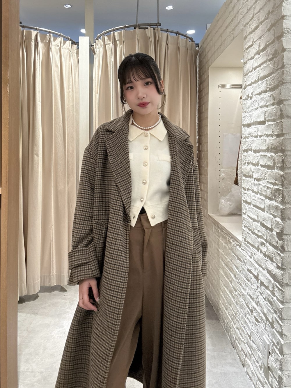 ホワイト系のニット/セーター、ブラウン系のスラックス、ベージュ系のチェスターコートを着用したレディースの冬コーディネートの3枚目の写真