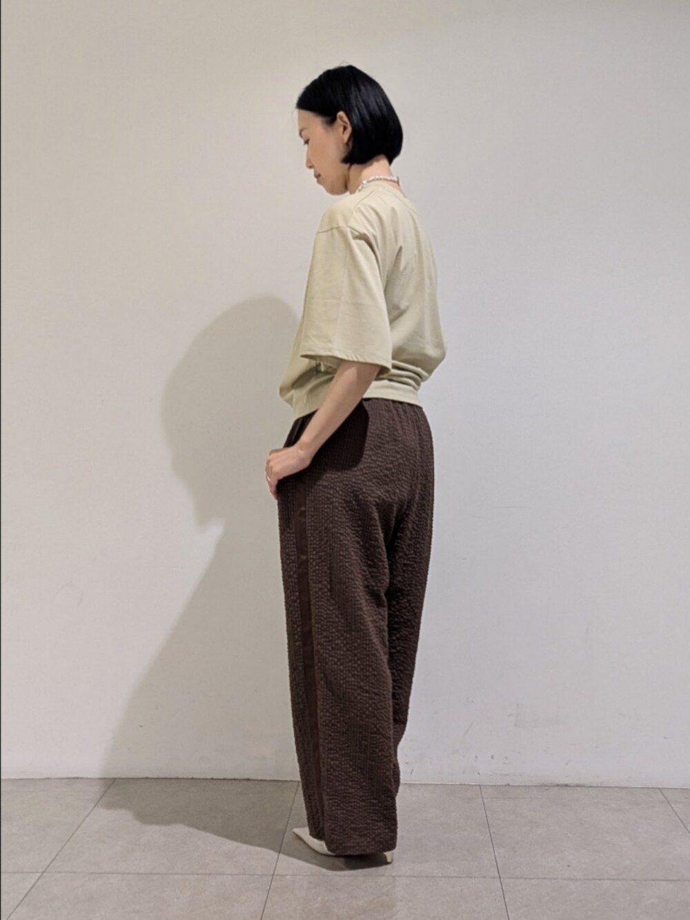 グリーン系のTシャツ/カットソー、ブラウン系のその他パンツ、ホワイト系のネックレスを着用したレディースの夏コーディネートの4枚目の写真