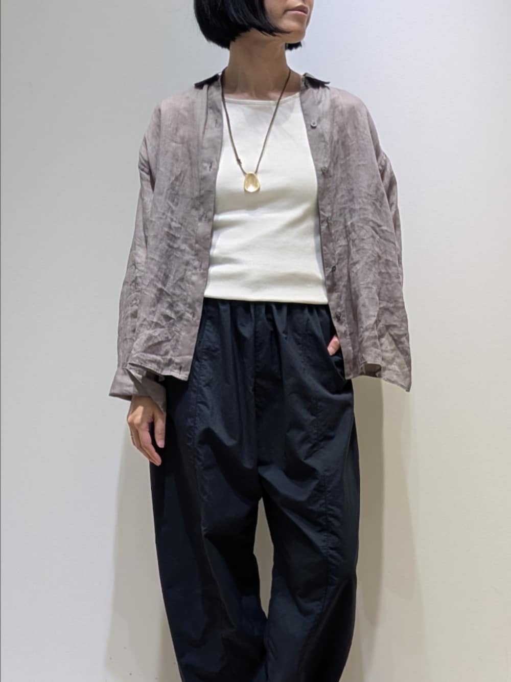 ブラウン系のシャツ/ブラウス、グレー系のその他パンツ、ゴールド系のネックレスを着用したレディースの春コーディネートの2枚目の写真