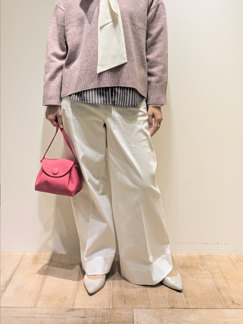 ピンク系のニット/セーター、ブラック系のシャツ/ブラウス、ホワイト系のデニムパンツを着用したレディースの冬コーディネートの3枚目の写真