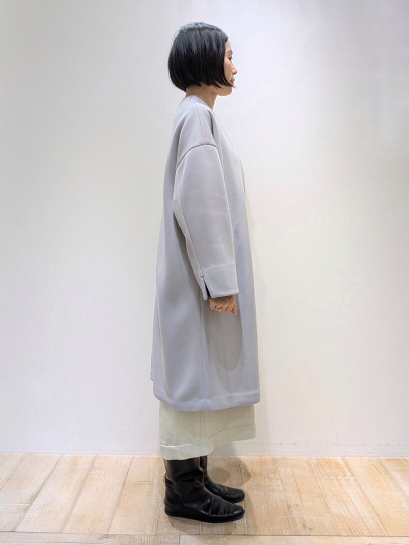 グレー系のノーカラーコート、ホワイト系のワンピースを着用したレディースの冬コーディネートの2枚目の写真