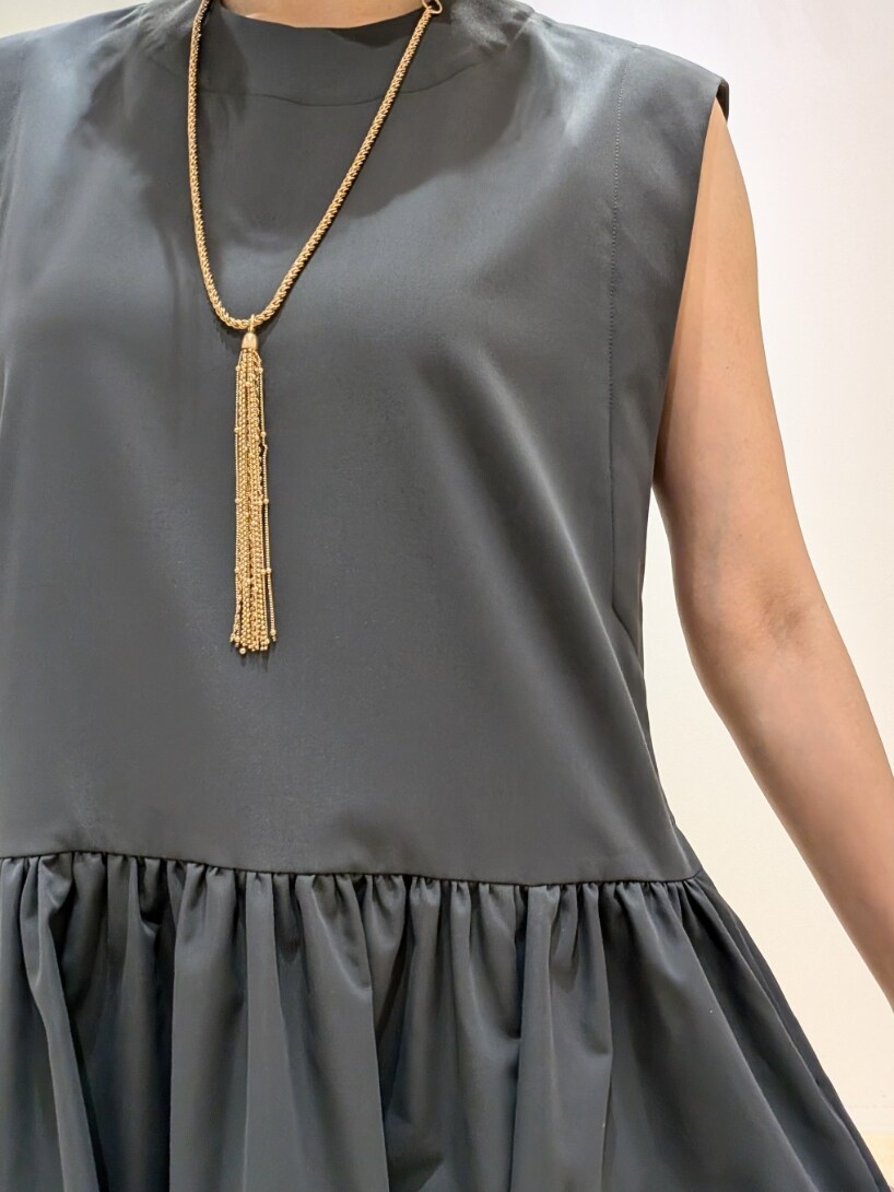 グレー系のワンピース、ゴールド系のネックレスを着用したレディースの夏コーディネートの4枚目の写真