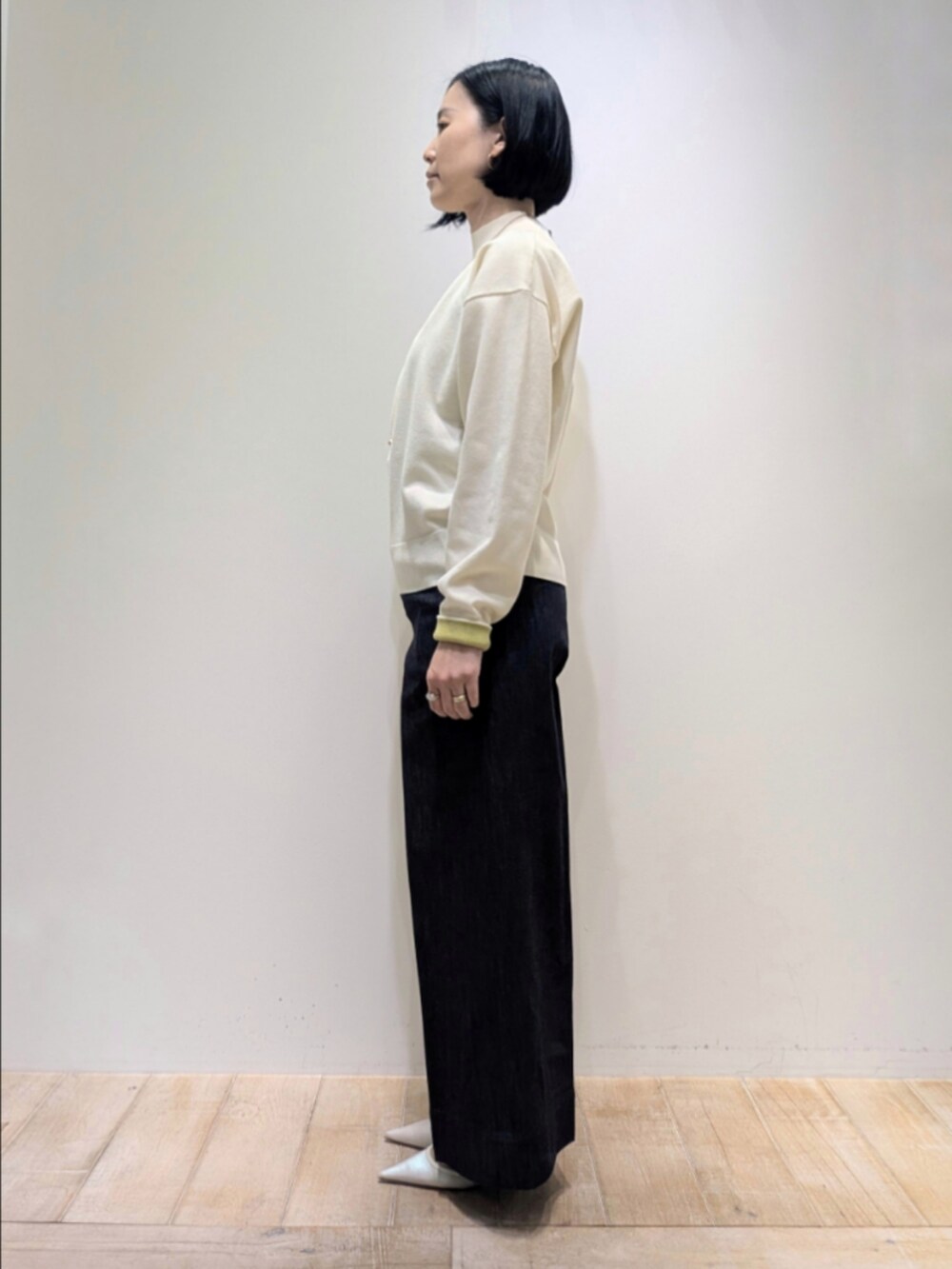 ホワイト系のニット/セーター、ブルー系のデニムパンツ、グリーン系のショルダーバッグを着用したレディースの冬コーディネートの4枚目の写真