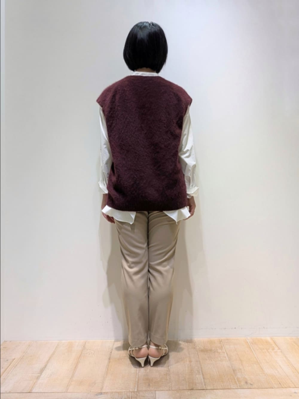 レッド系のベスト、ホワイト系のシャツ/ブラウス、ベージュ系のその他パンツを着用したレディースの秋コーディネートの5枚目の写真
