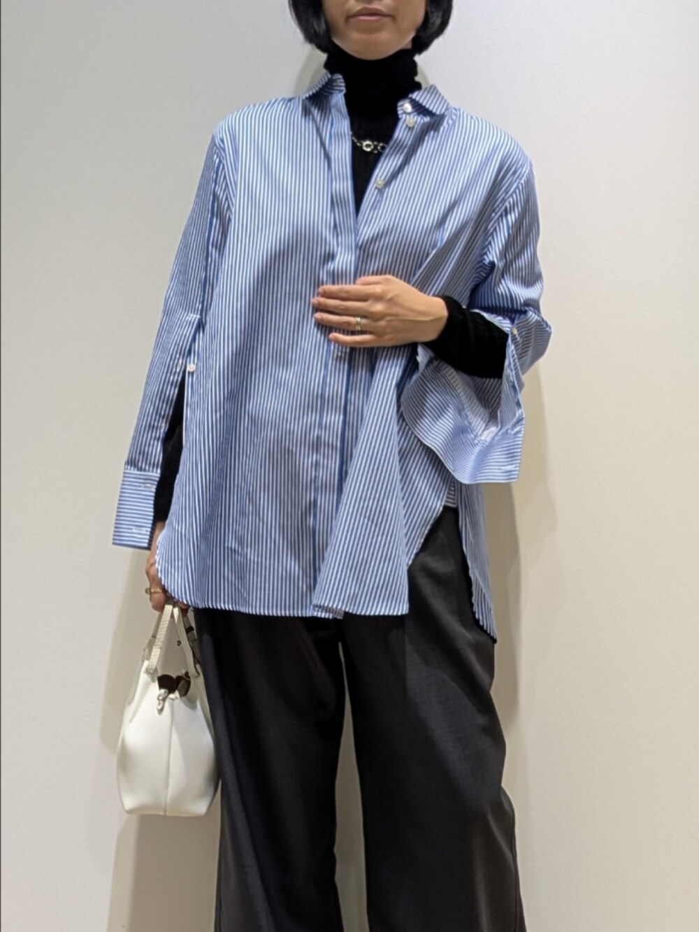 ブルー系のシャツ/ブラウス、ブラック系のニット/セーター、グレー系のその他パンツを着用したレディースの秋コーディネートの2枚目の写真