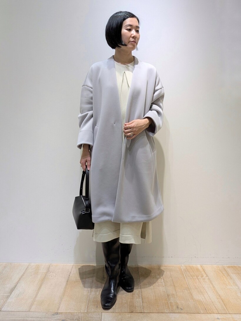 グレー系のノーカラーコート、ホワイト系のワンピースを着用したレディースの冬コーディネートの4枚目の写真